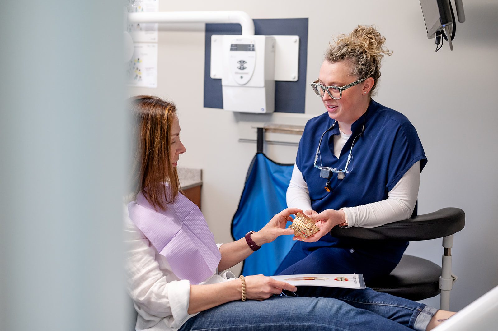 A dentist explaining tooth replacement options with a dental model