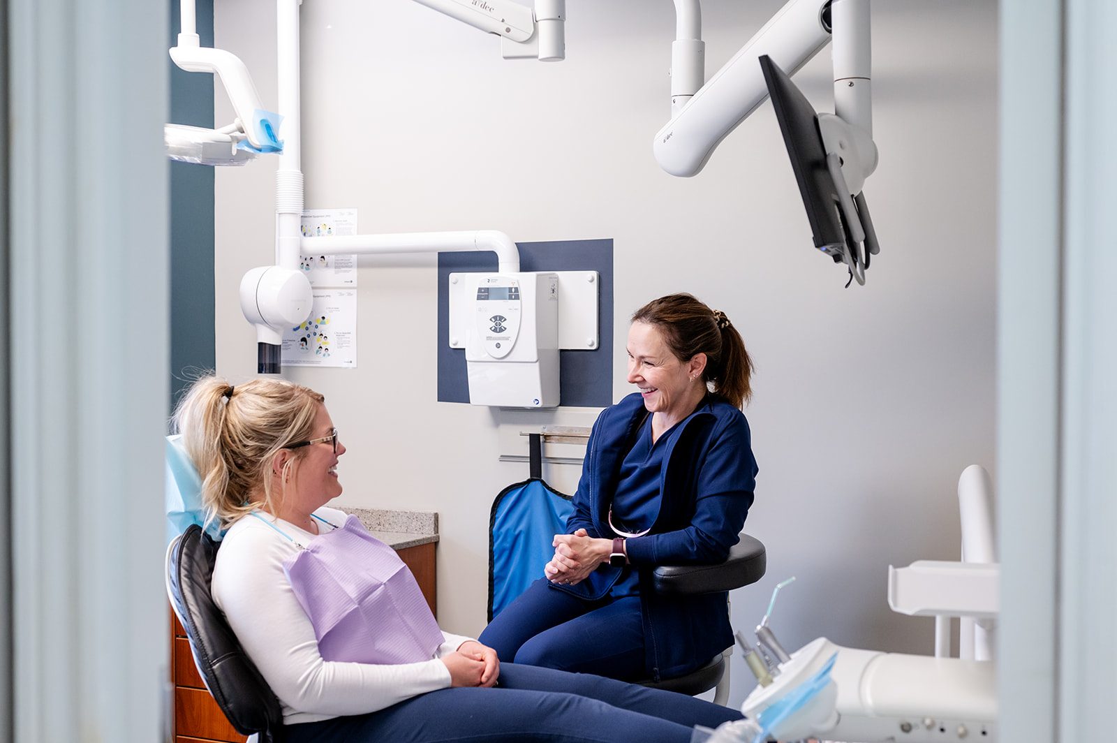 A dentist sitting with a patient in the treatment room, talking through a visit at Dearness Family Dentistry