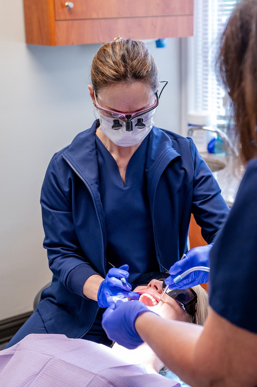 A dentist providing precise treatment with loupes in the operatory