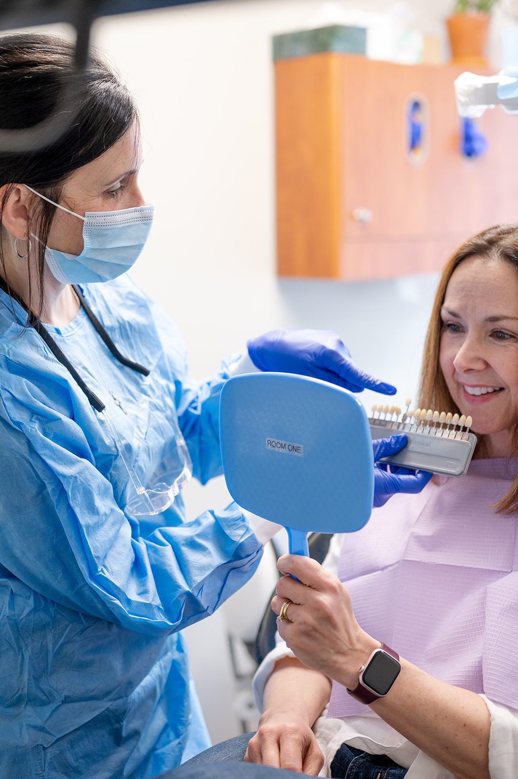 A patient reviewing their smile in a mirror with a team member during a cosmetic visit